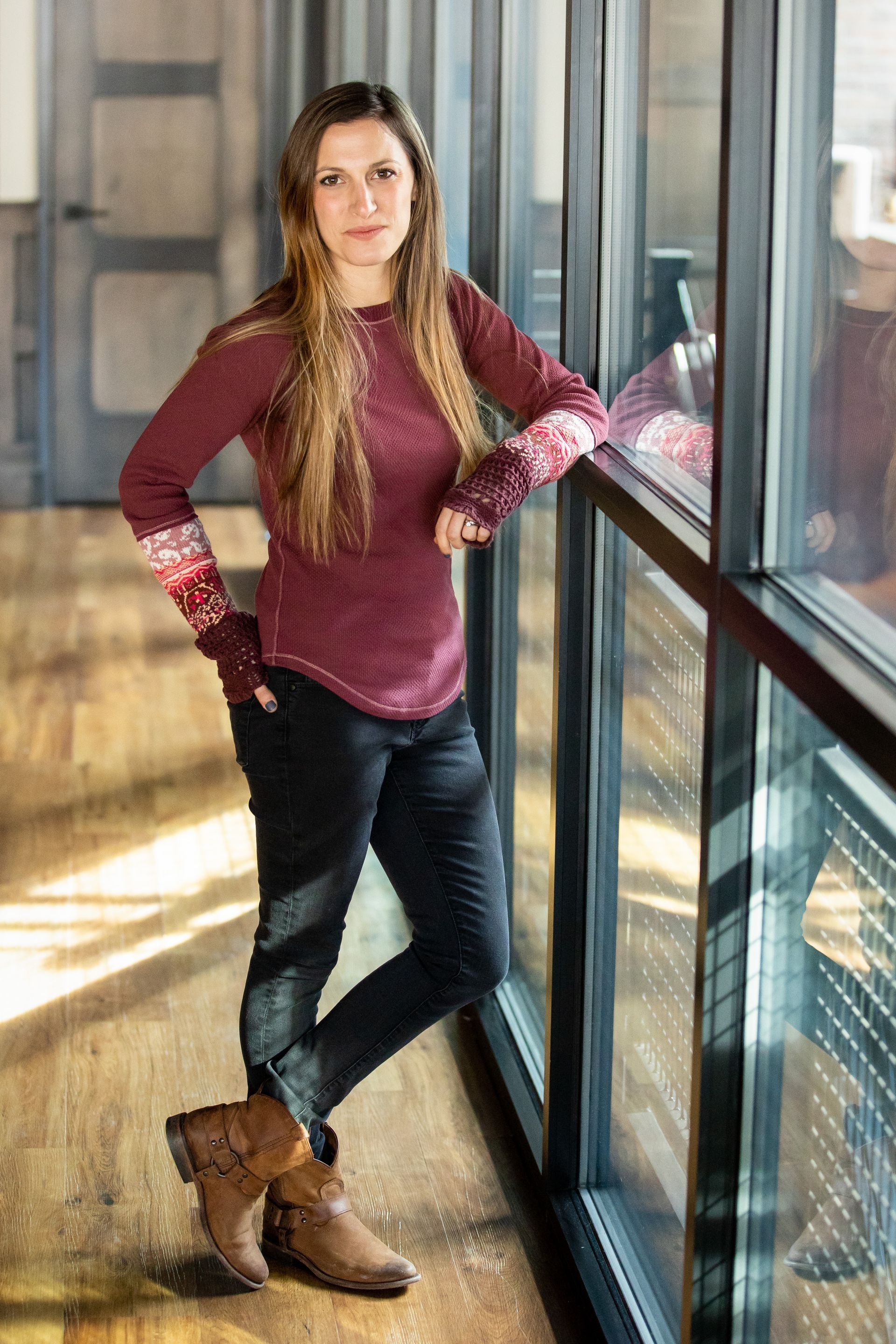 A woman is leaning against a window in a hallway.
