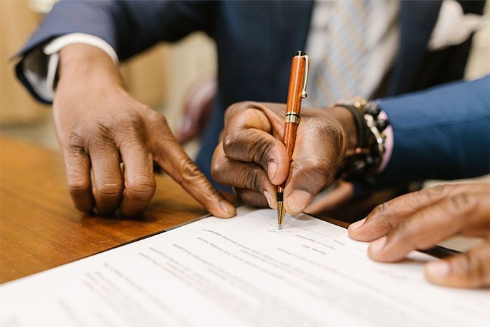 hands of an attorney and client signing a document