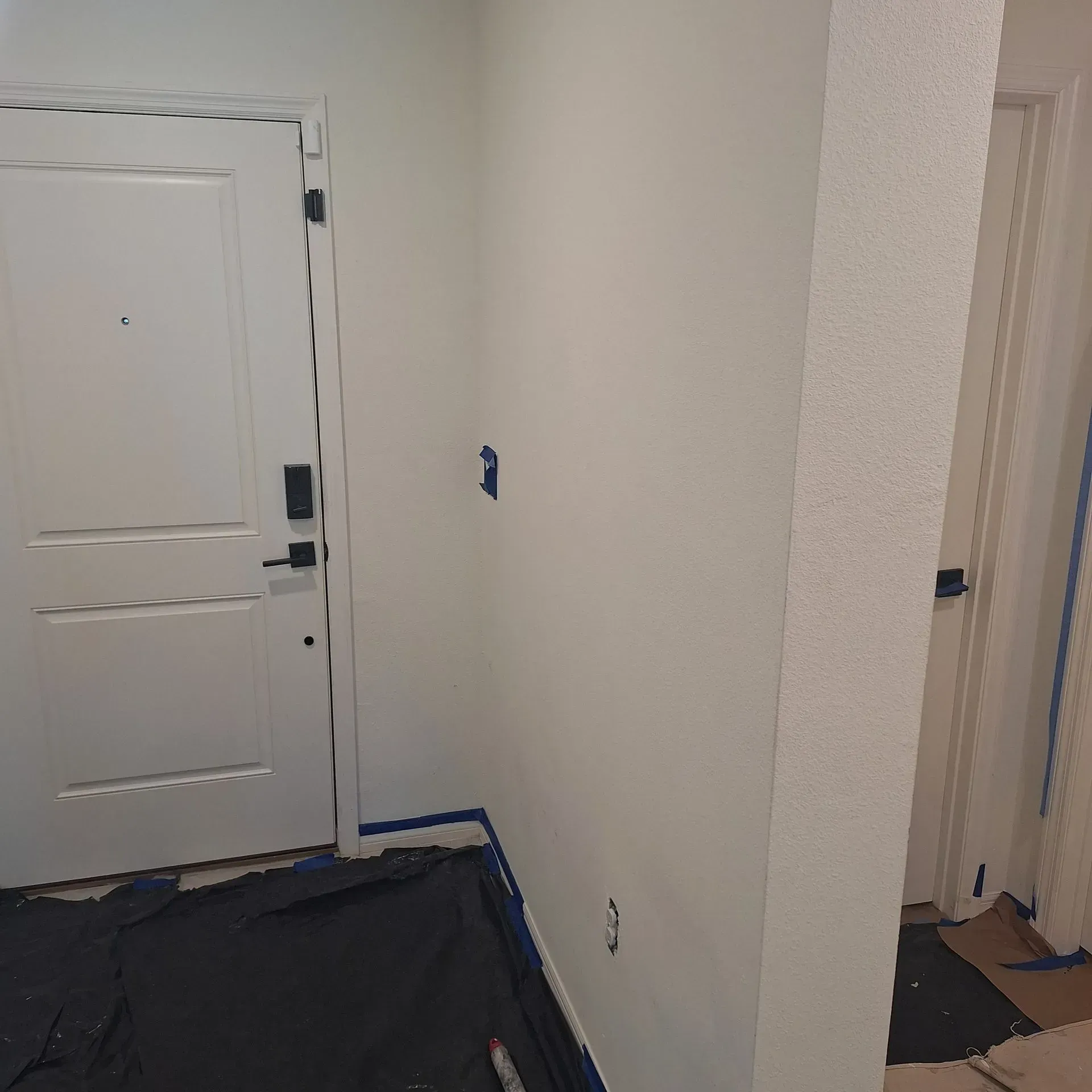 A hallway with a white door and a black door handle.