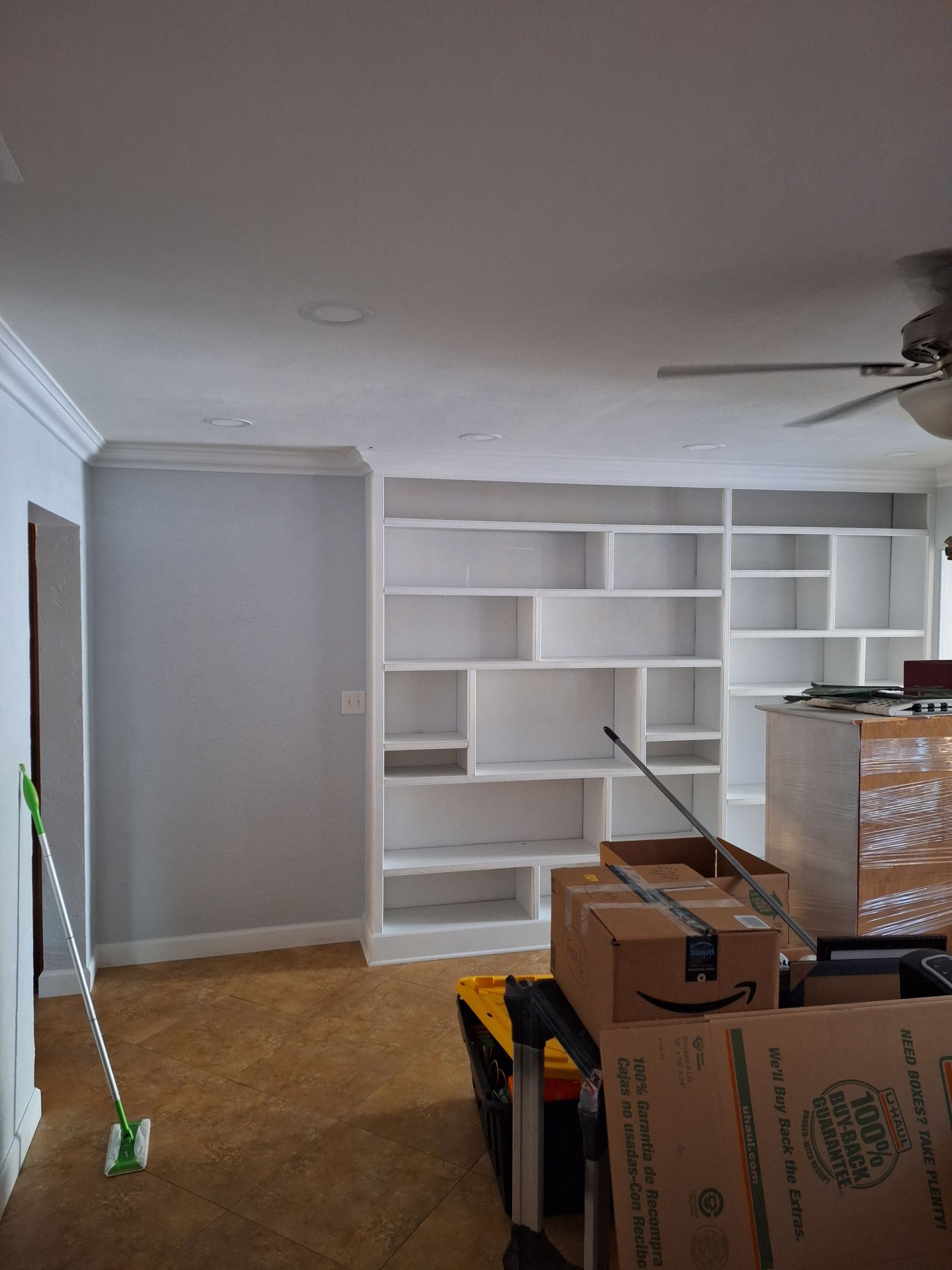 A living room filled with boxes and a ceiling fan