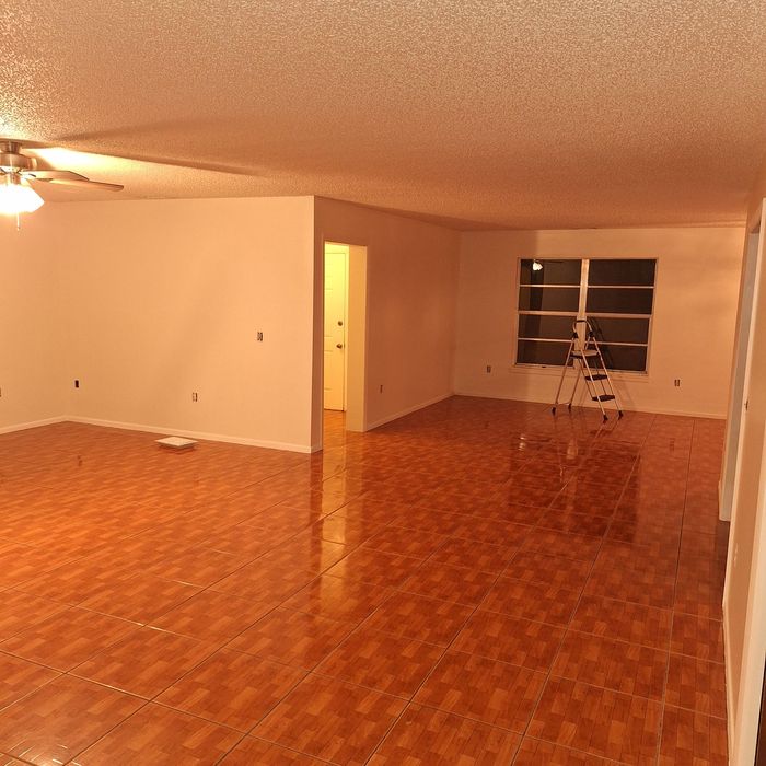 An empty living room with a wooden floor and white walls