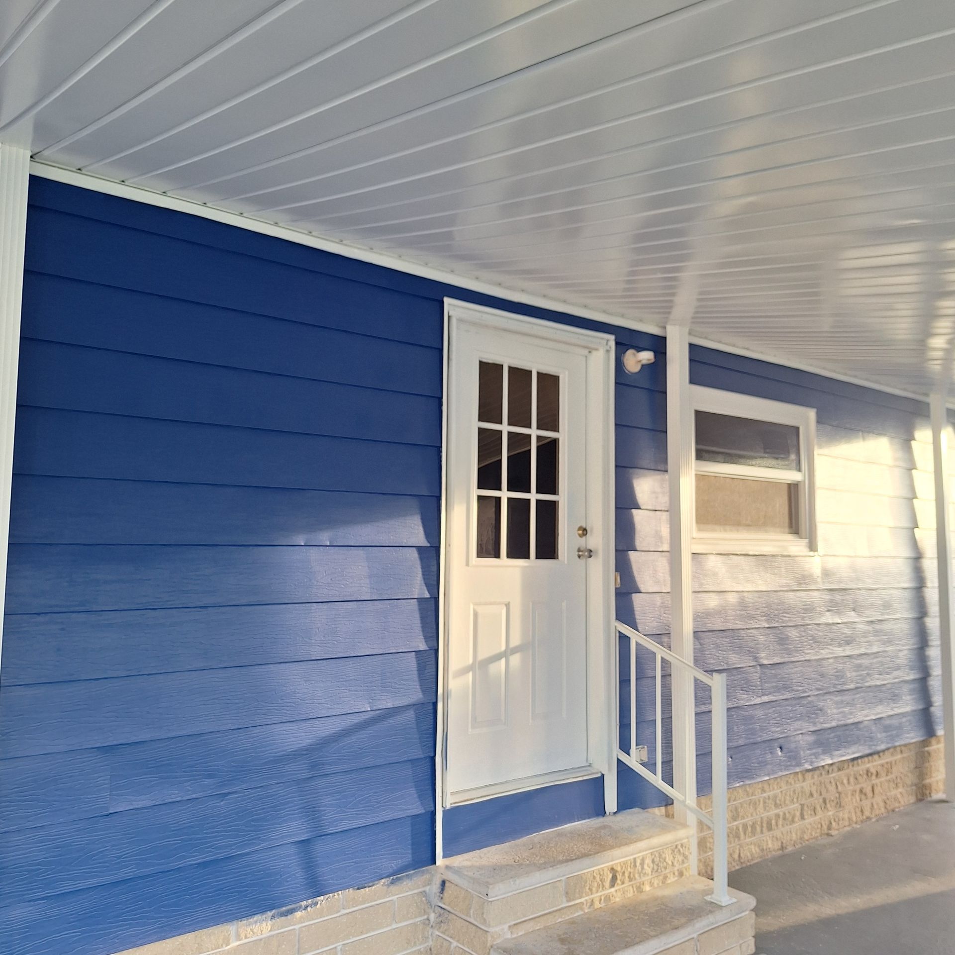 A blue house with a white door and stairs