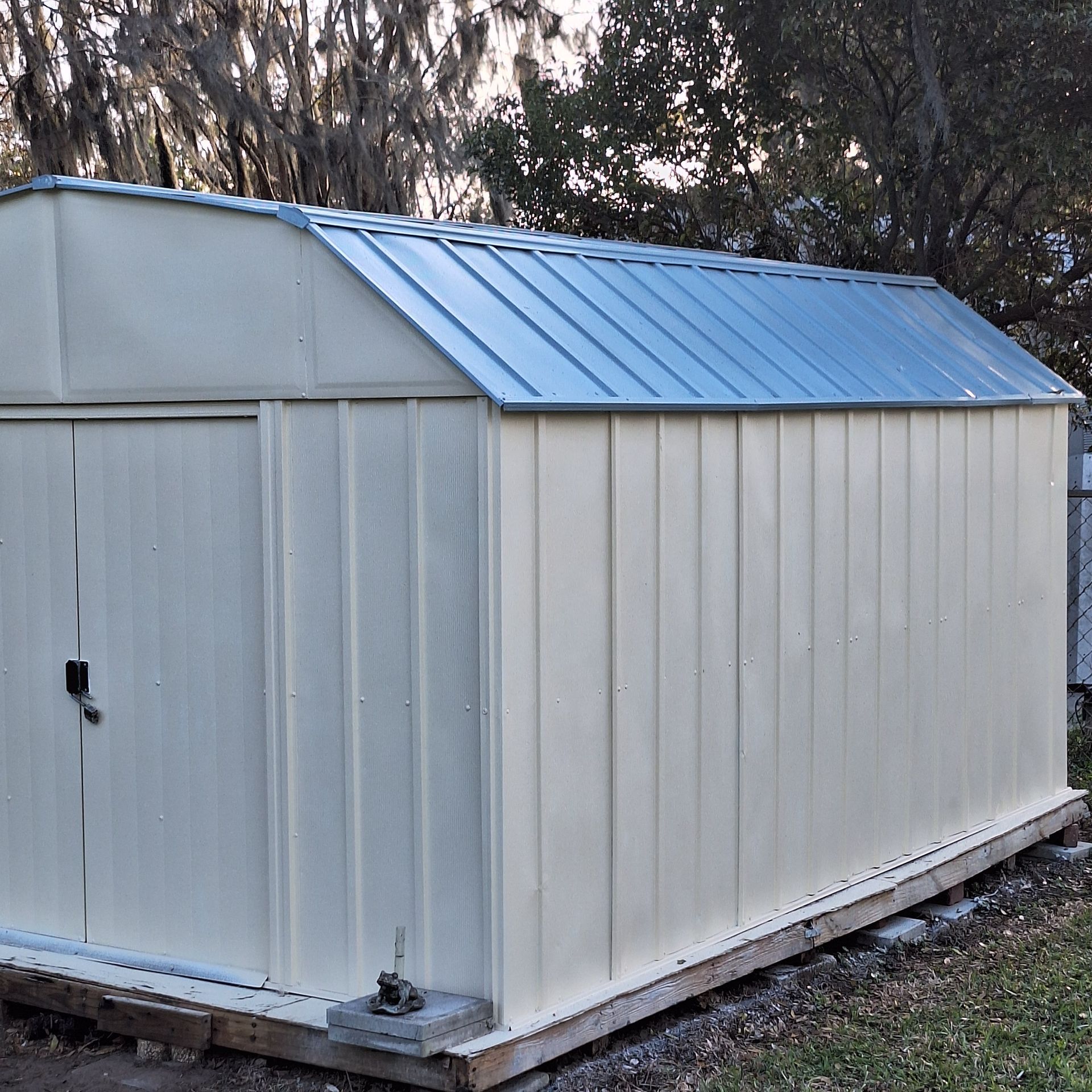 A white shed with a blue roof sits in the grass