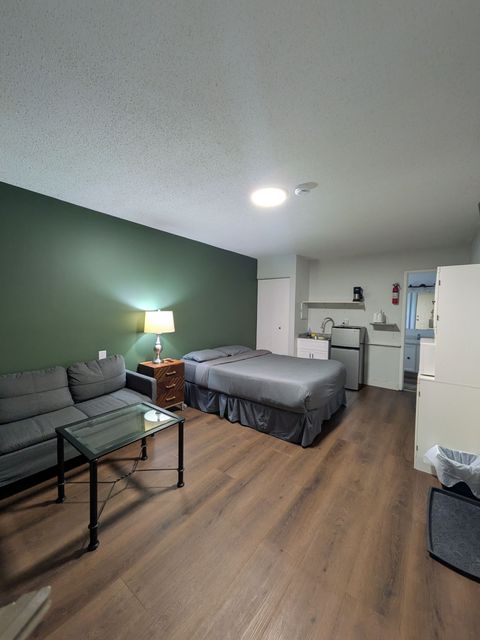 A hotel room with a bed , desk , chair and lamp.