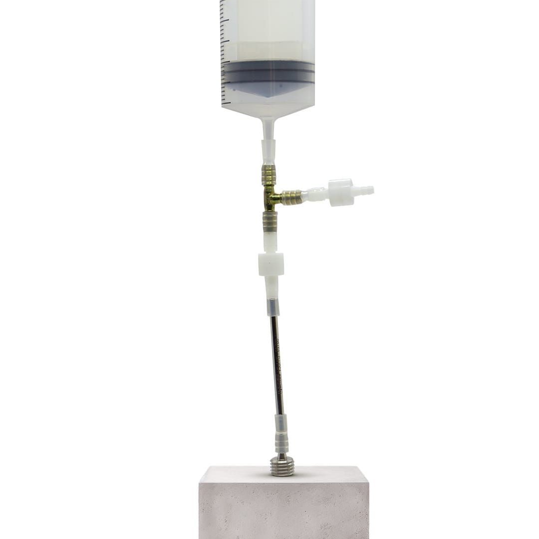 Clear syringe and tubing assembly mounted on a concrete block for fluid testing.
