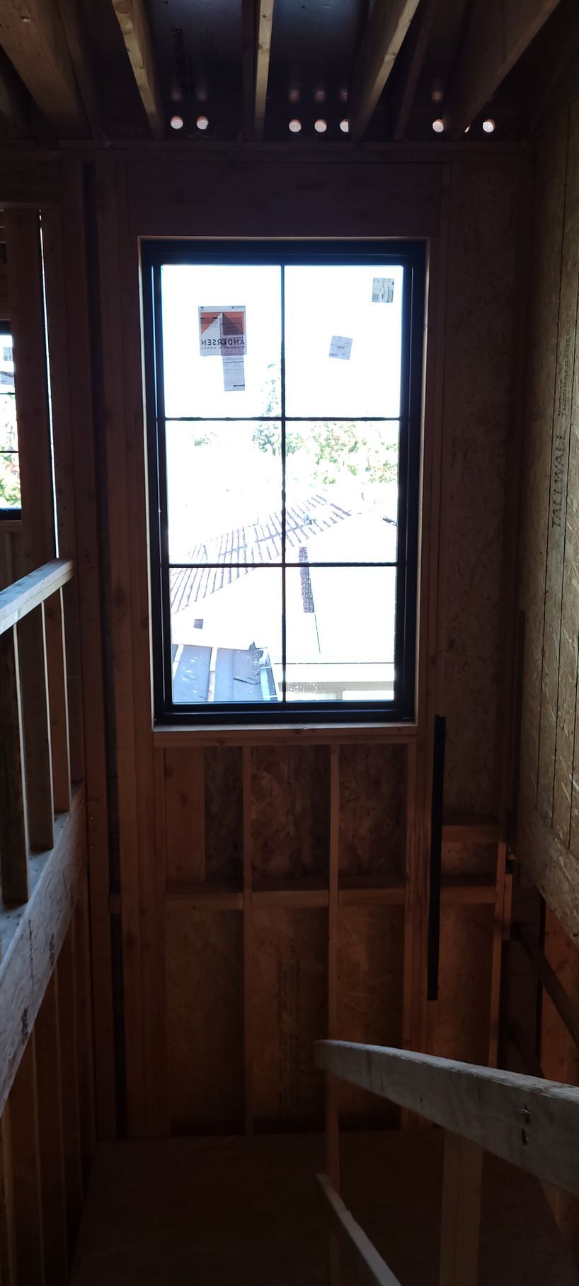 Interior view of a wooden stairwell with a large window at the top.