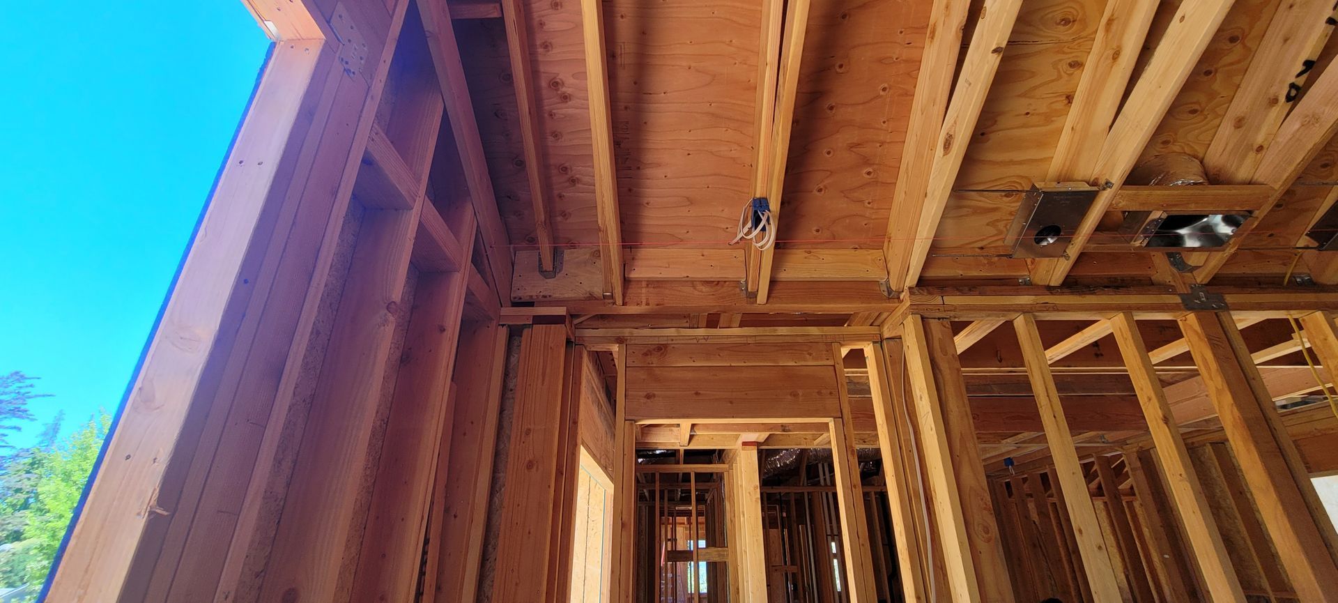 Wooden framework of a building under construction, including walls, ceiling, and doorway.