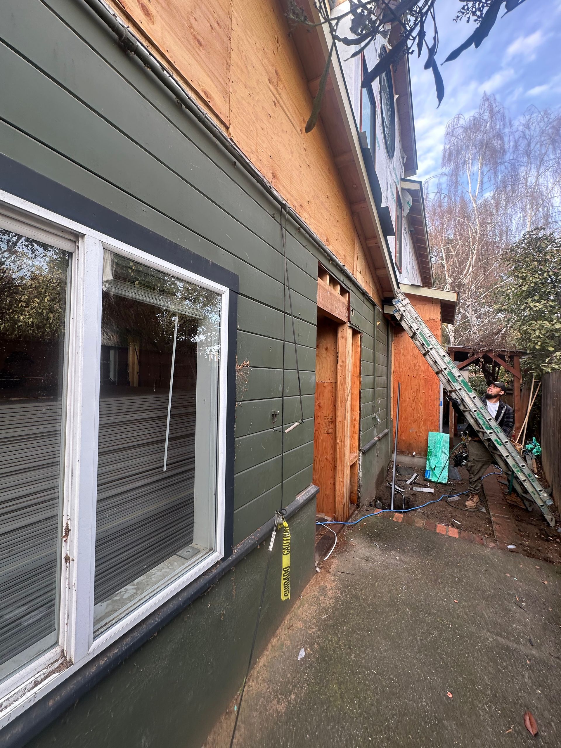 House exterior under construction; green siding installed. 