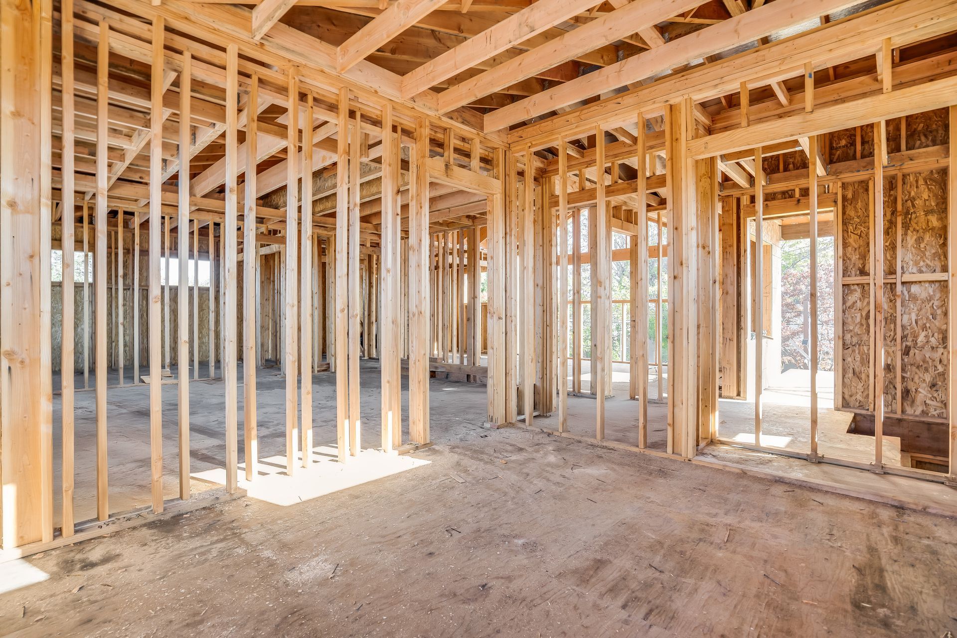 Interior view of a building frame under construction with wooden studs and exposed rafters.