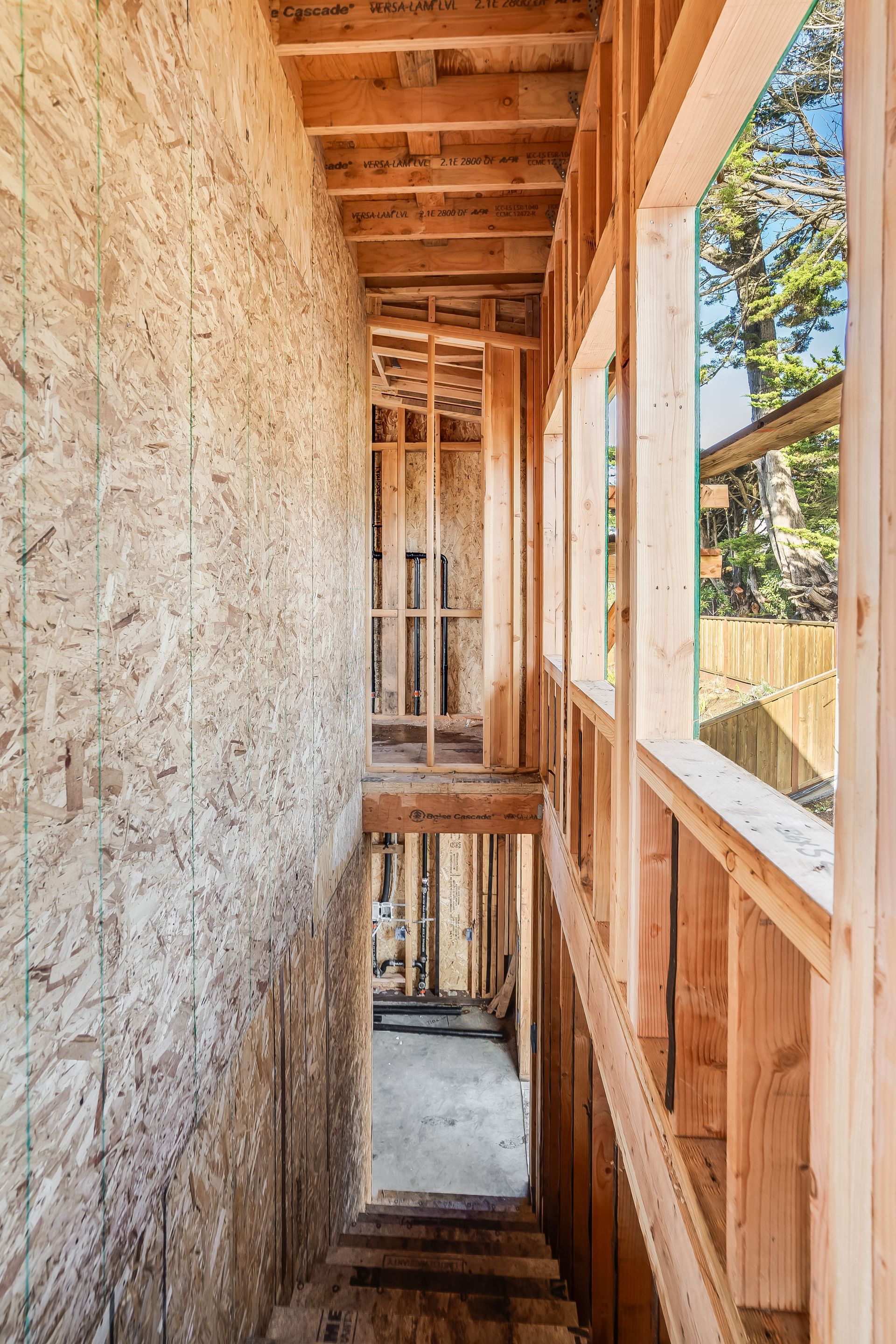Interior view of a building under construction, showing wooden framing for walls, stairs, and windows.