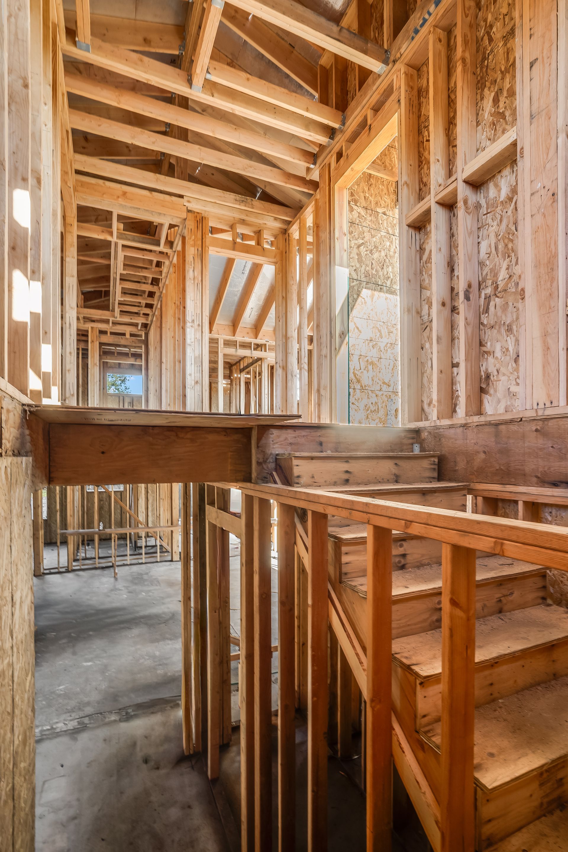 Interior view of a house under construction; wooden framing with stairwell and walkways.