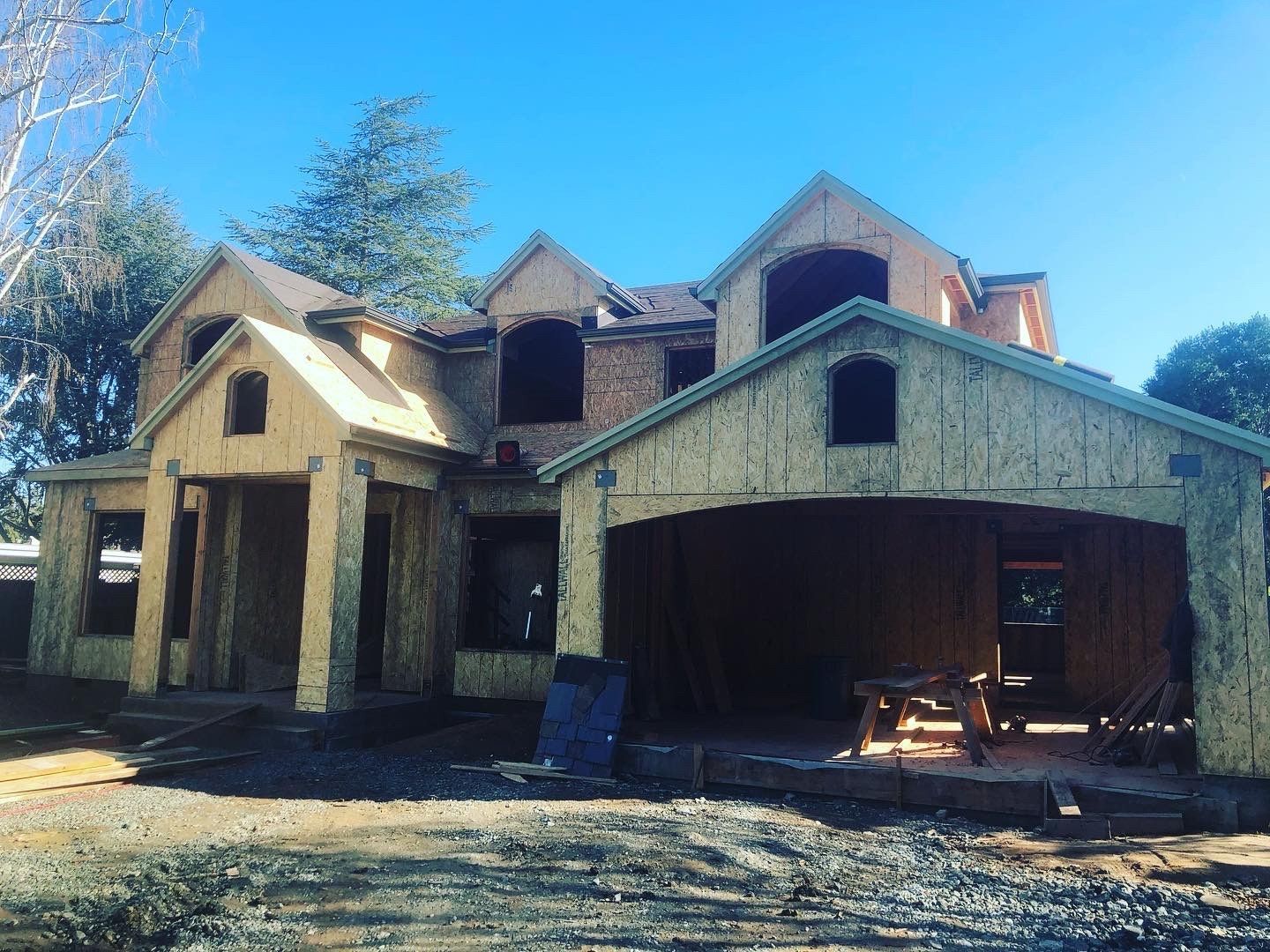 House under construction, wood frame, blue sky. Garage attached.
