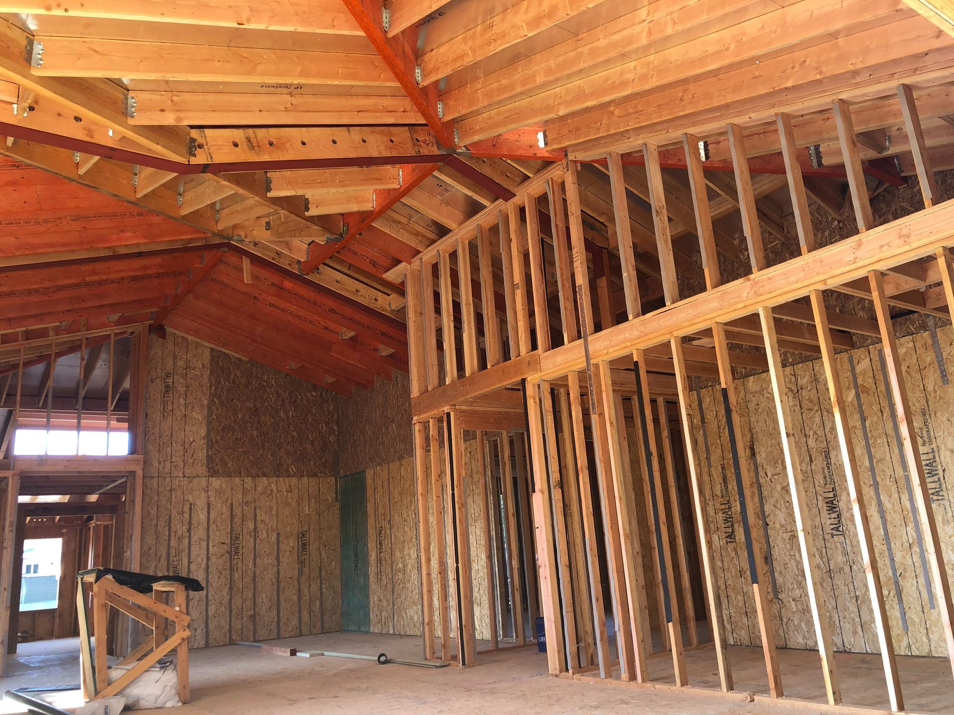 Interior view of a building under construction, showing wooden framing for walls, roof, and possibly a second floor or loft.
