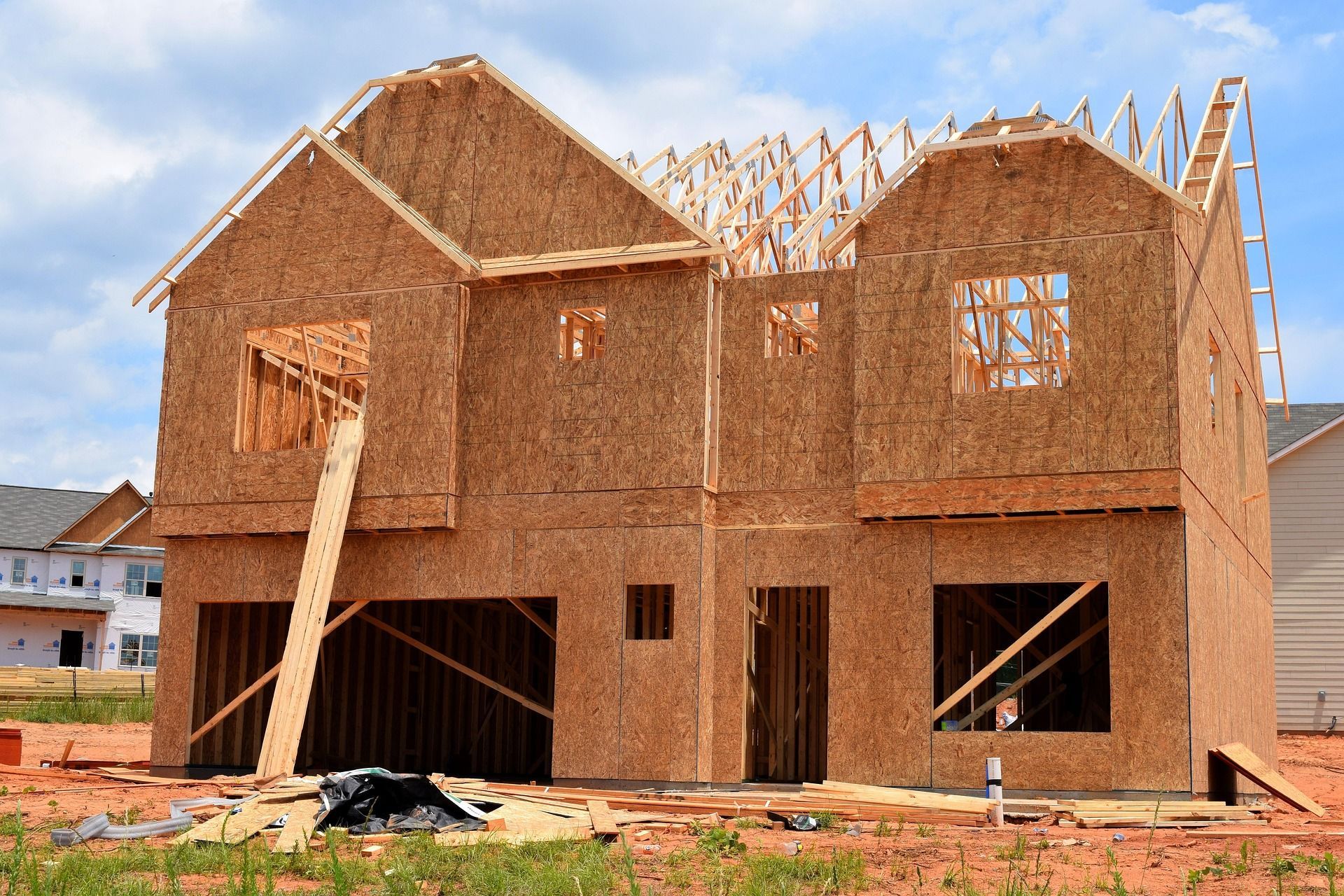 Two-story house under construction, with wooden frame and oriented strand board (OSB) sheathing.