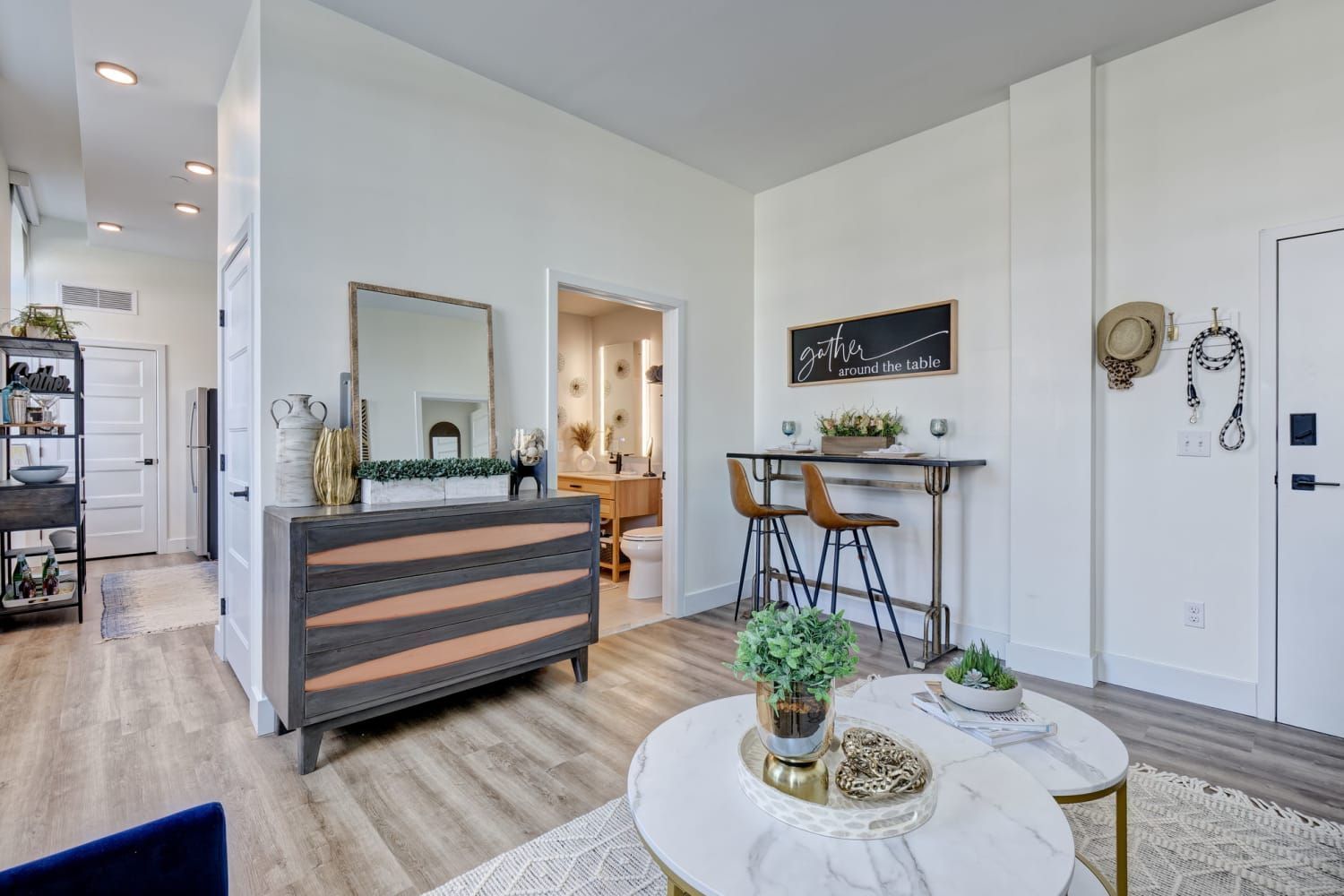 A living room with two coffee tables , a dresser , a mirror and a table.