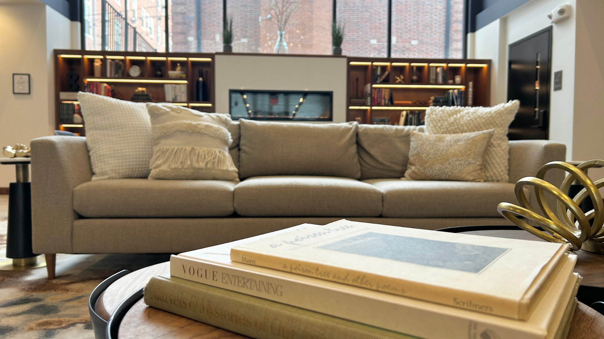 A modern luxury based lobby with a couch, many pillows, and a table with books
