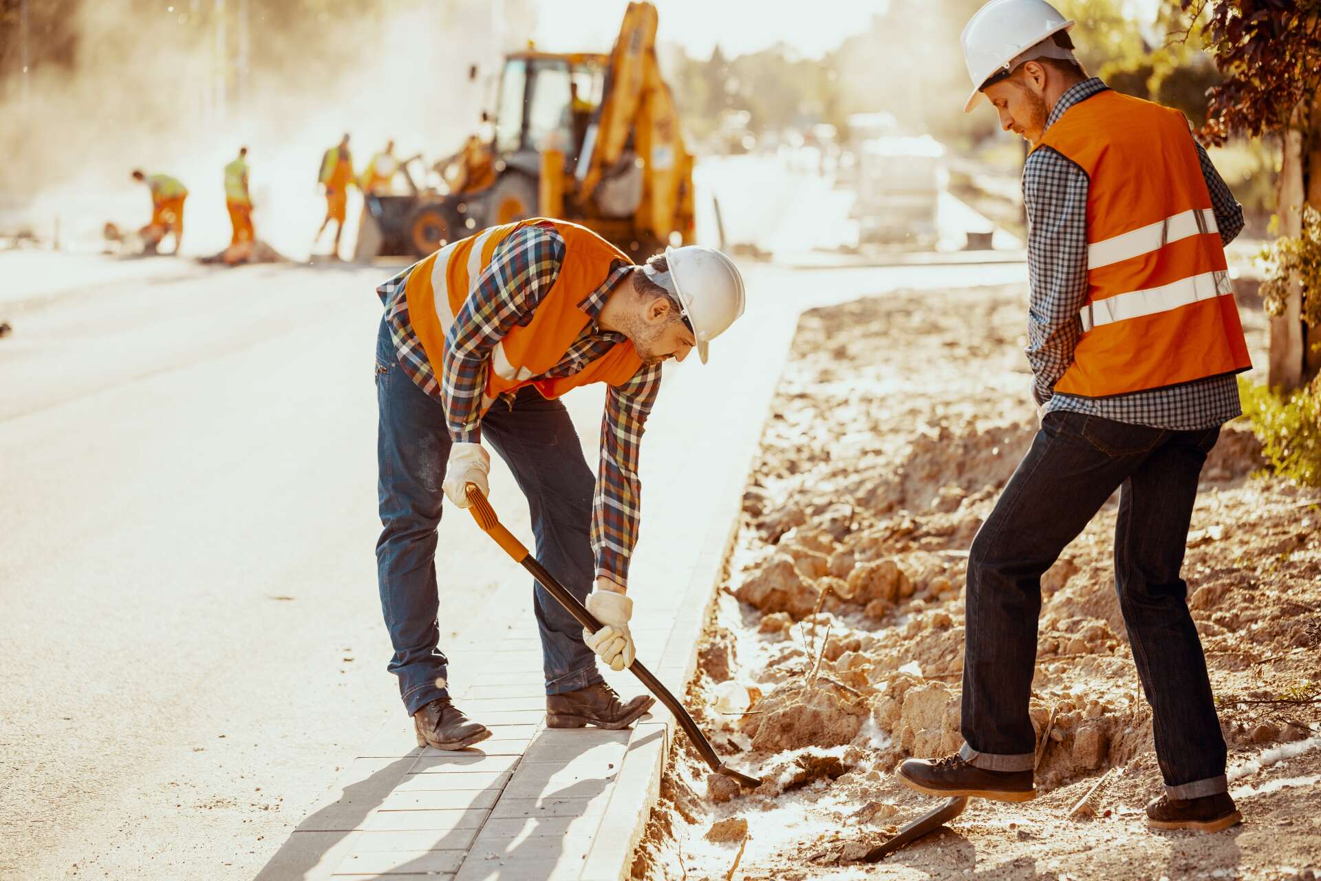 workers in reflective vests using shovels during construction