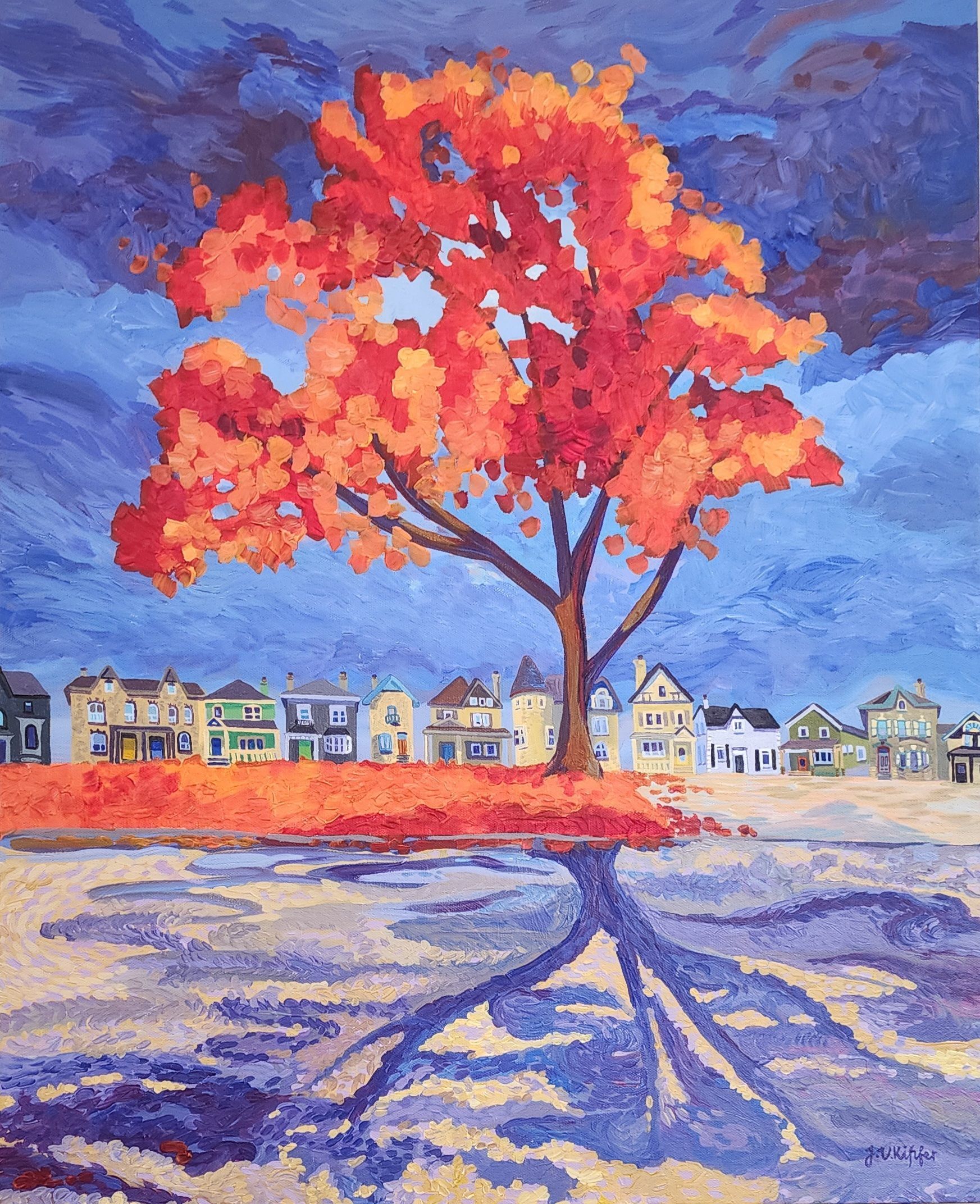 Bright red-orange tree with reflection in a blue field, houses in the background under a cloudy sky.