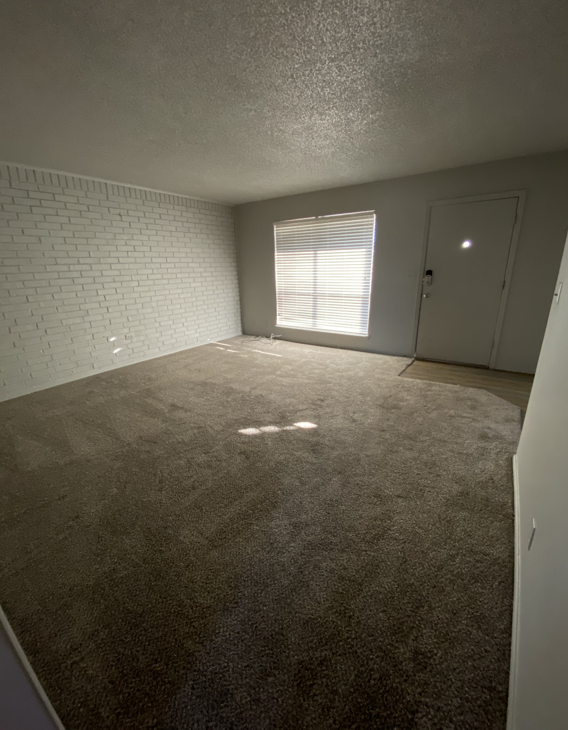 an empty living room with a large window and a door .