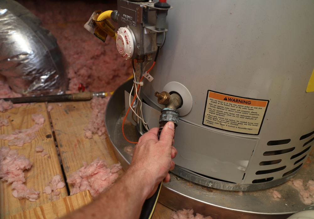 A Person is Fixing a Water Heater in an Attic — Absolute Plumbing Australia in Howard Spring, NT