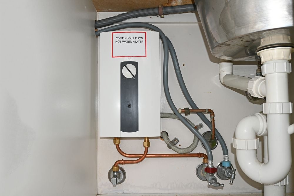 A Water Heater is Installed Under a Sink in a Kitchen — Absolute Plumbing Australia in Howard Spring, NT