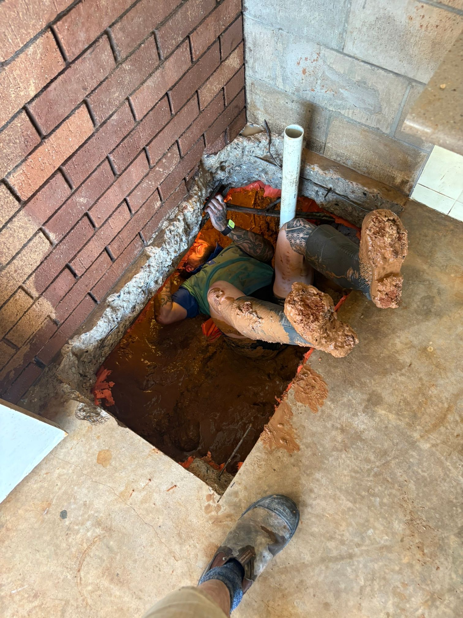A Plumber is Fixing a Pipe in a hole in the ground — Absolute Plumbing Australia in Howard Spring, NT