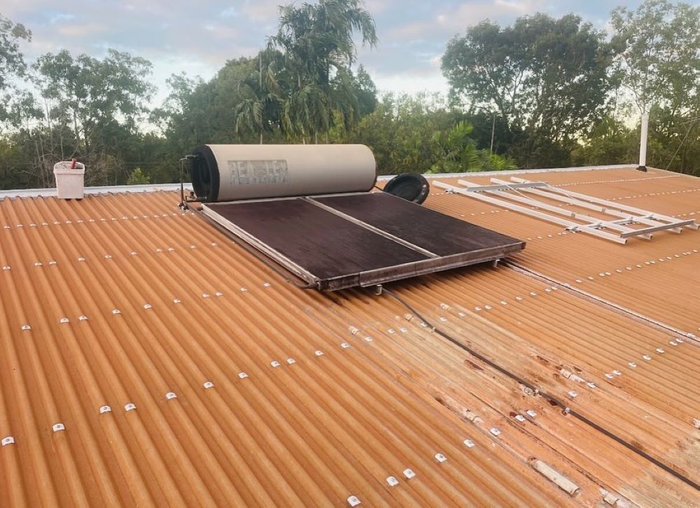 A Solar Water Heater is Sitting on Top of a Roof — Absolute Plumbing Australia in Howard Spring, NT