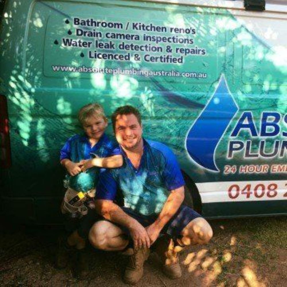 A Man and a Child Are Kneeling in Front of an Abs Plumber Van — Absolute Plumbing Australia in Howard Spring, NT