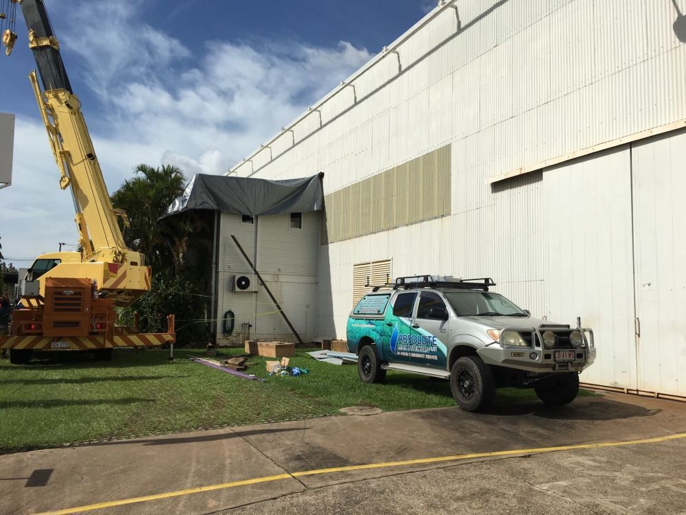A Truck is Parked in Front of a Building With a Crane in the Background — Absolute Plumbing Australia in Howard Spring, NT