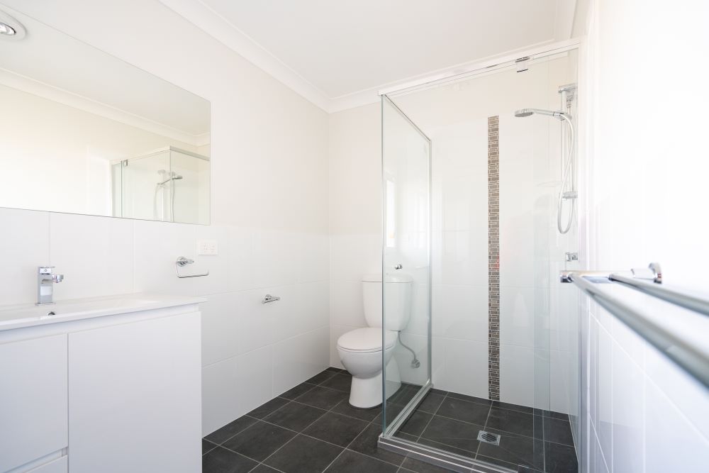 A Bathroom With a Toilet, Sink, Mirror and Walk in Shower — Absolute Plumbing Australia in Howard Spring, NT