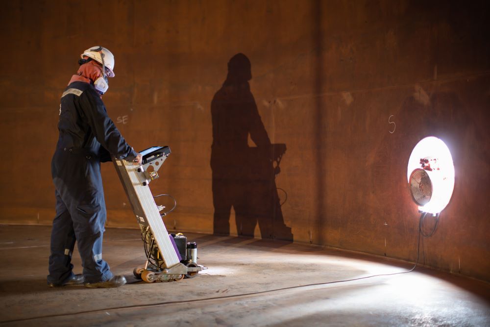 A Man is Working on a Machine in a Dark Room — Absolute Plumbing Australia in Howard Spring, NT