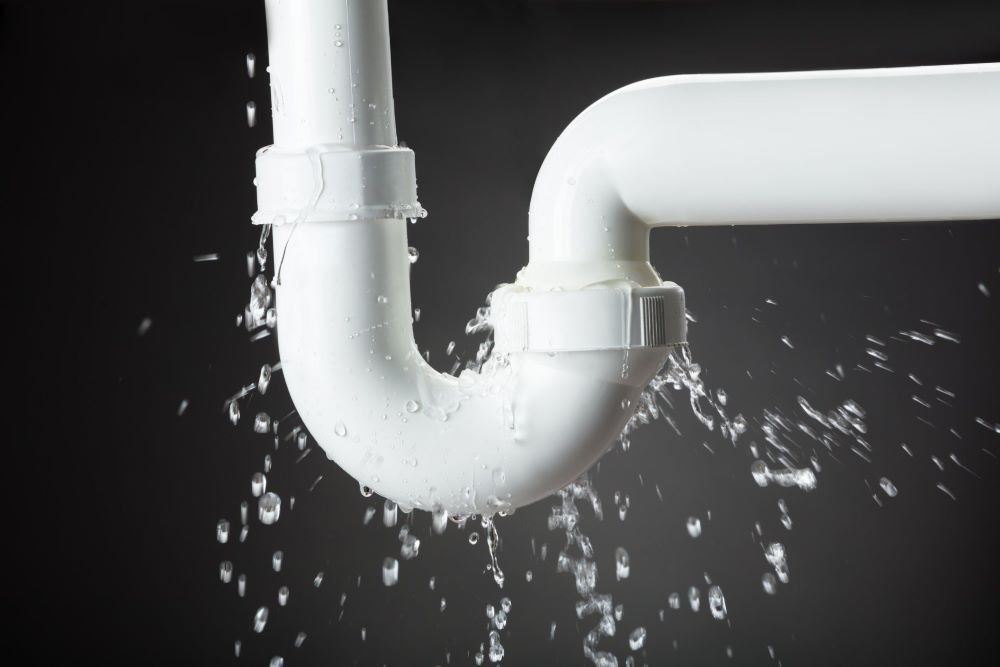 A White Pipe is Leaking Water on a Black Background — Absolute Plumbing Australia in Leanyer, NT