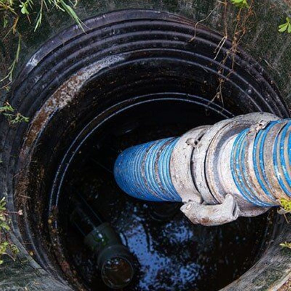 A Blue Hose is Coming Out of a Manhole Cover — Absolute Plumbing Australia in Leanyer, NT