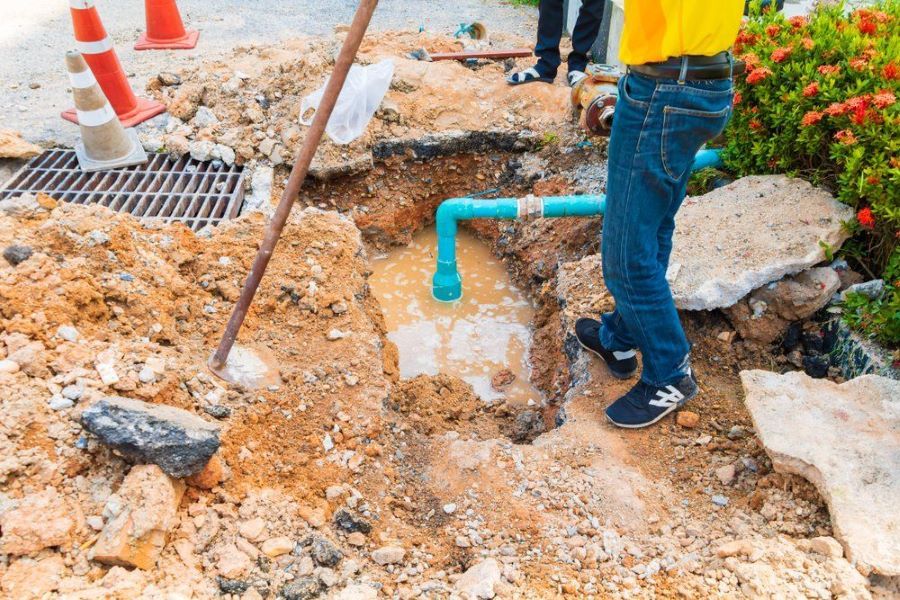 A Man is Standing in the Dirt Next to a Pipe — Absolute Plumbing Australia in Nightcliff, NT