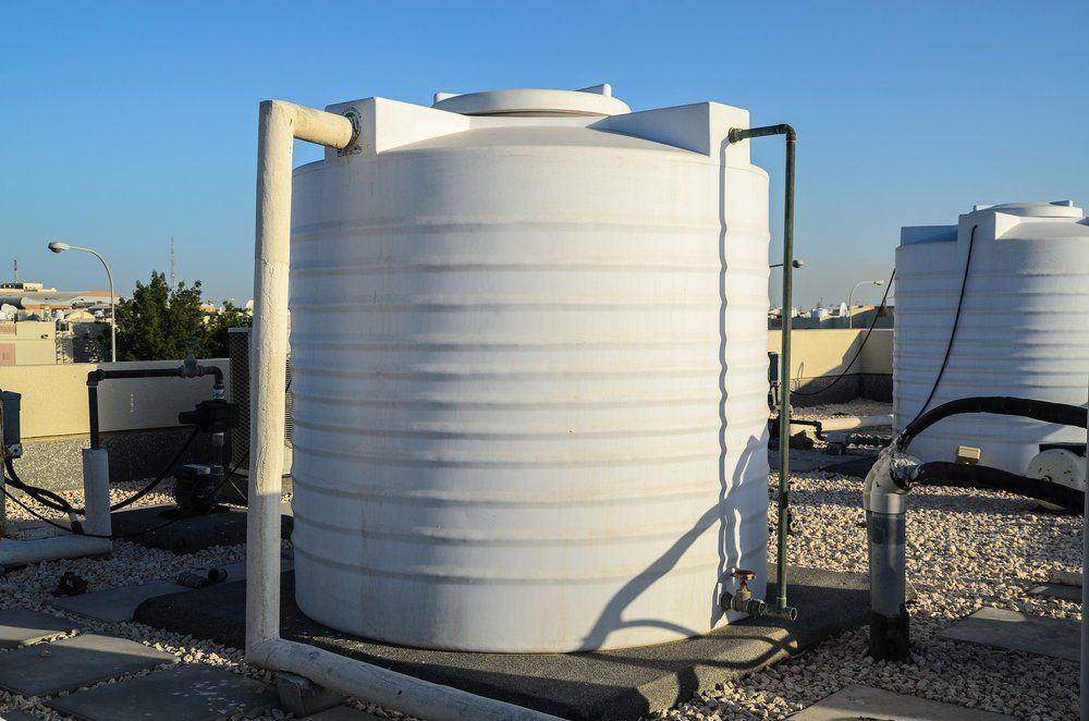 A Large White Water Tank is Sitting on Top of a Gravel Ground — Absolute Plumbing Australia in Palmerston, NT