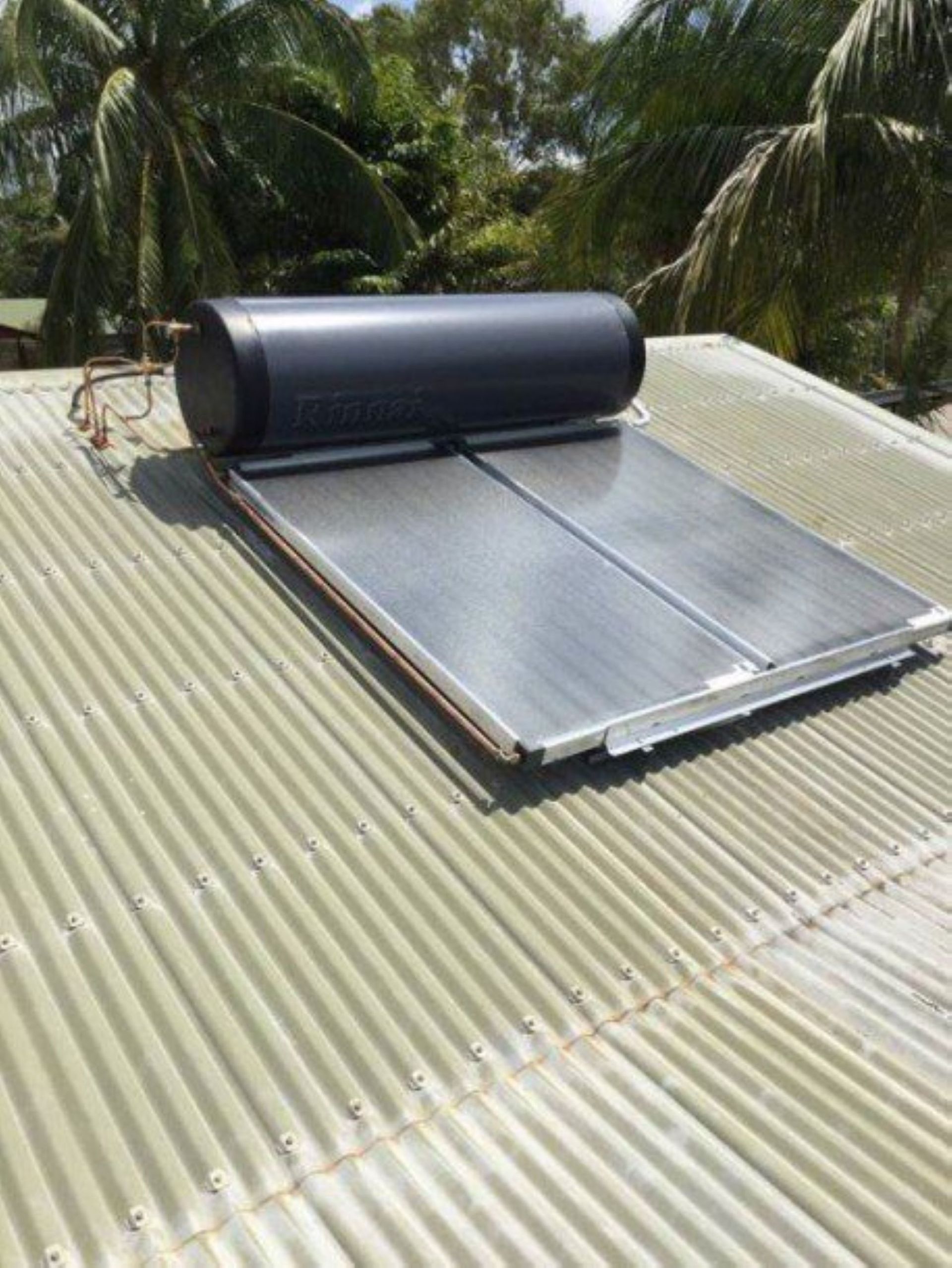 A Solar Water Heater is Sitting on Top of a Corrugated Metal Roof — Absolute Plumbing Australia in Palmerston, NT