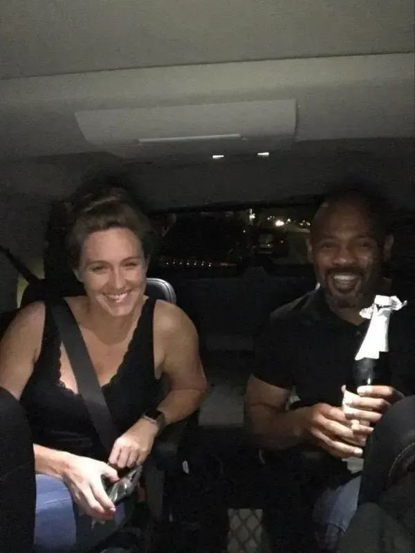 A man and a woman are sitting in the back seat of a car