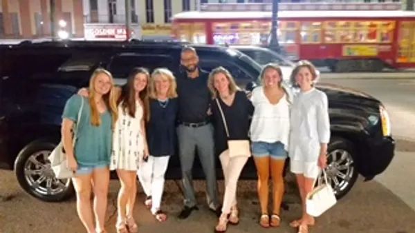 A group of people are posing for a picture in front of a limousine.