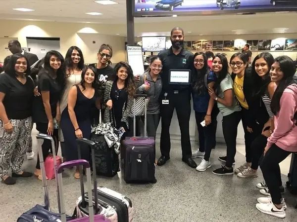 A group of people are posing for a picture at an airport.