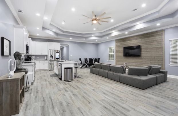 A living room with a couch, television and a ceiling fan.