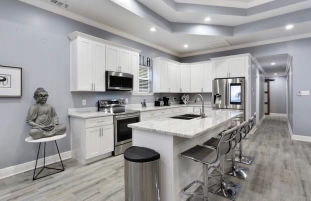 Modern kitchen with white cabinets, stainless steel appliances, and a Buddha statue.