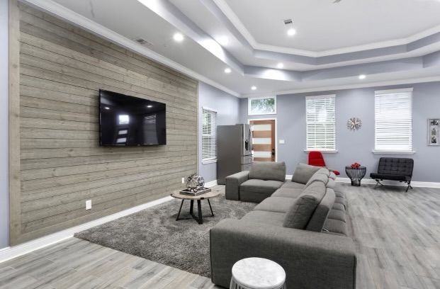 Modern living room with gray sectional sofa, wood-paneled wall with TV, and rug.