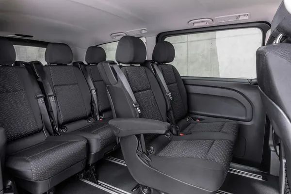 The back seat of a van with a lot of seats and arm rests.