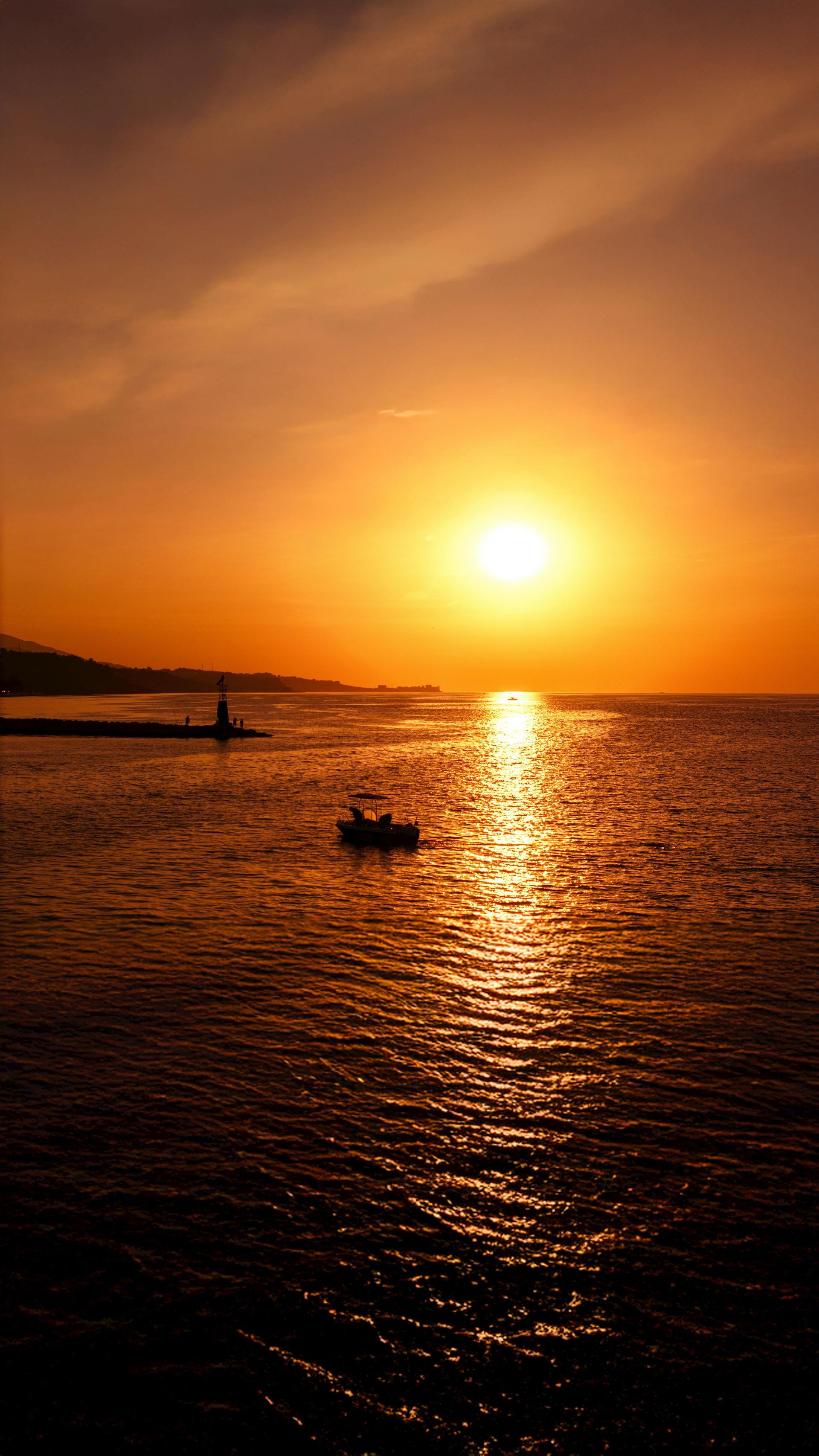 Coucher de soleil sur l'eau avec un bateau en silhouette.