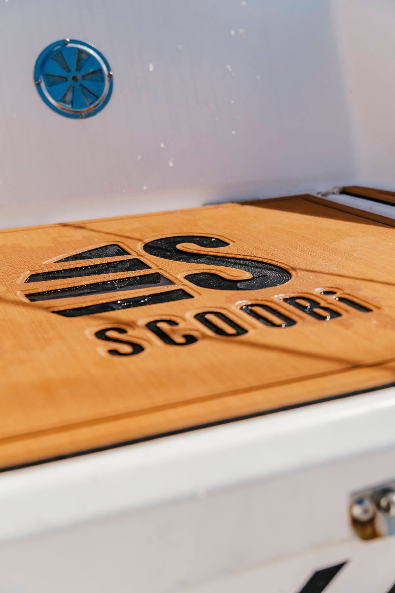 Gros plan sur une surface en cuir marron avec le mot « SCOORS » en relief et le logo à l'intérieur d'un boîtier blanc.