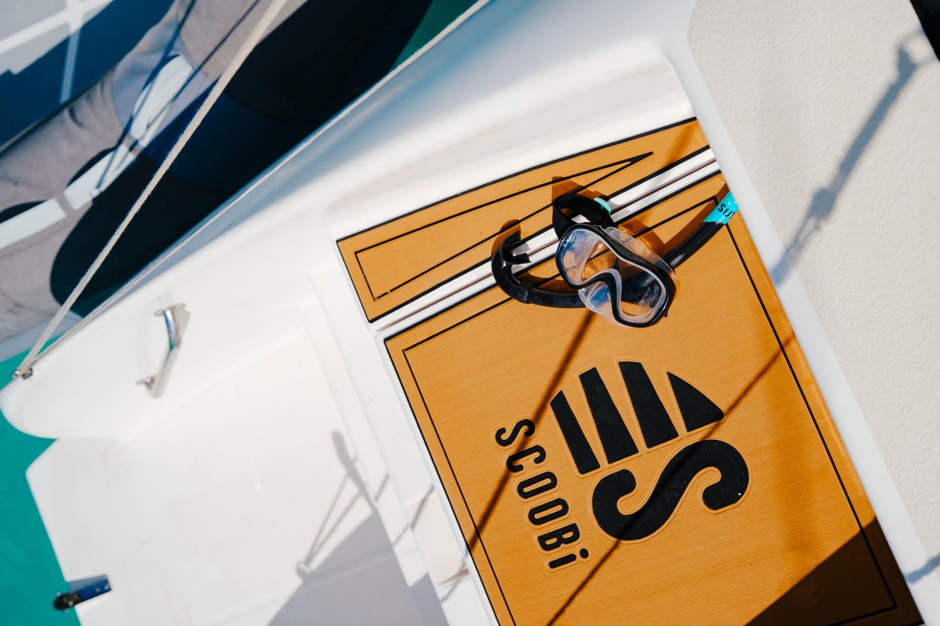 Pont de bateau avec tapis beige et lunettes de protection. « SCOOBI » et « SC008i » imprimés sur le tapis.