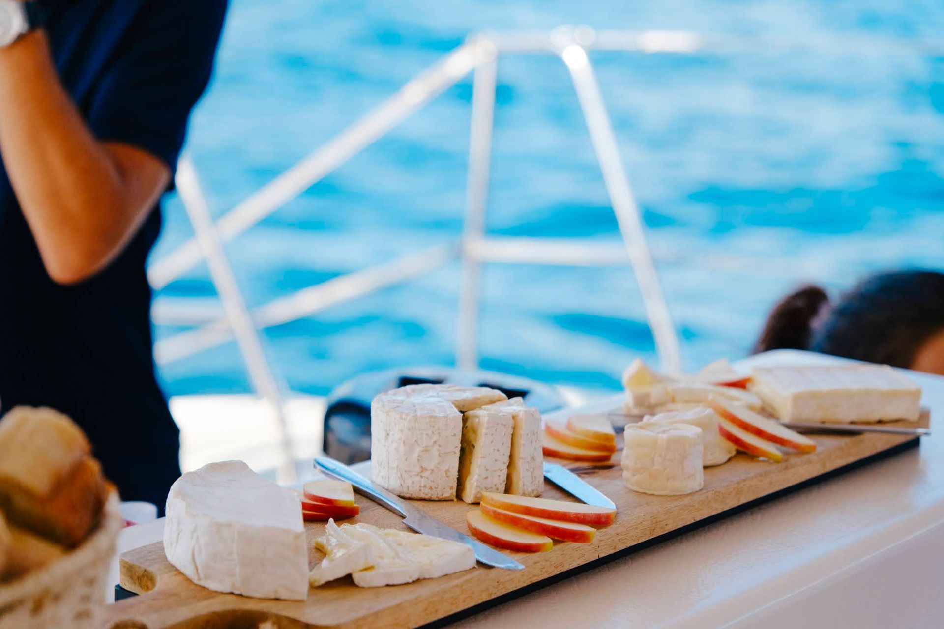 Plateau de fromages et de fruits sur un bateau, avec l'océan en arrière-plan.