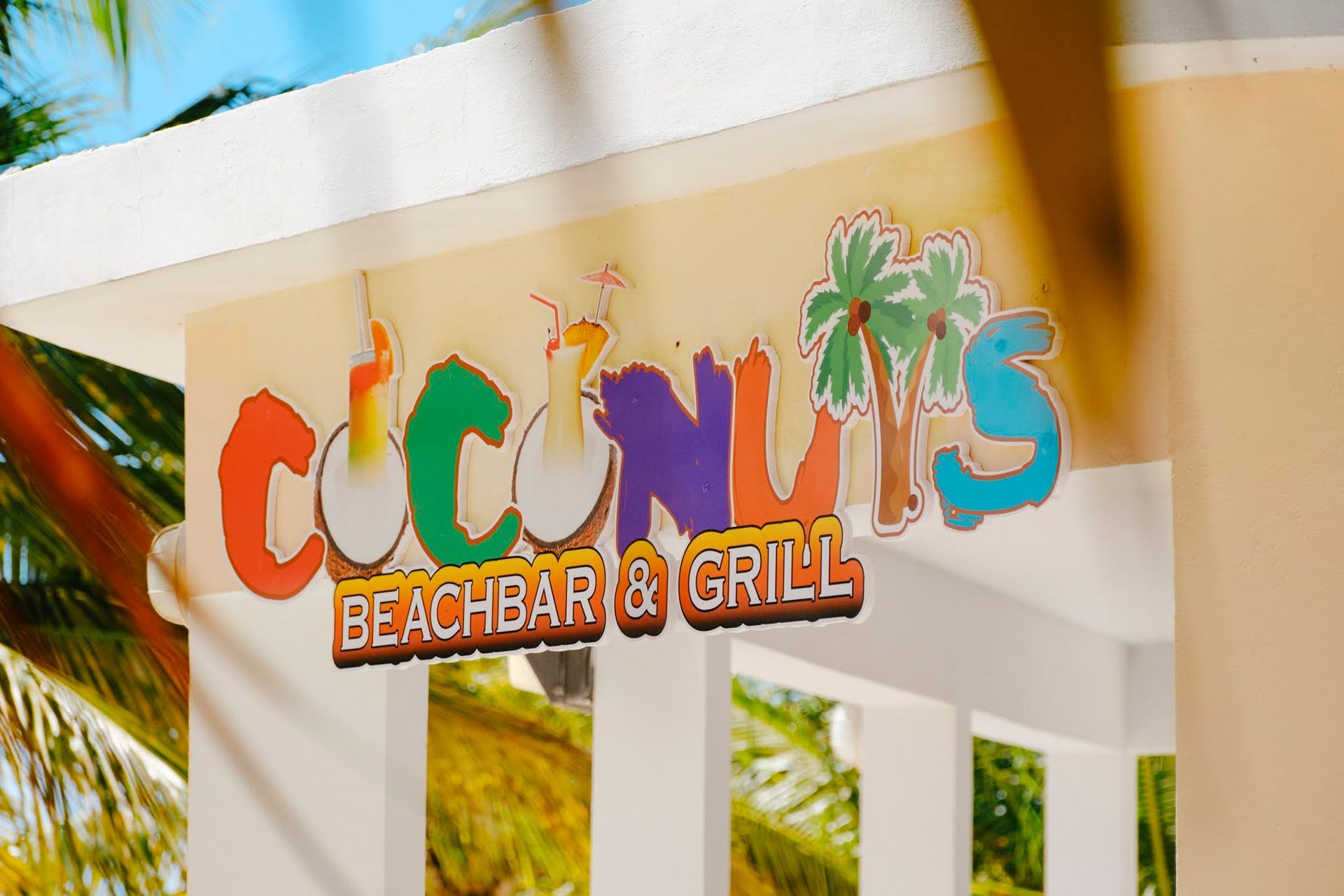 Sign for Coconuts Beachbar & Grill with colorful logo of coconuts and palm trees.