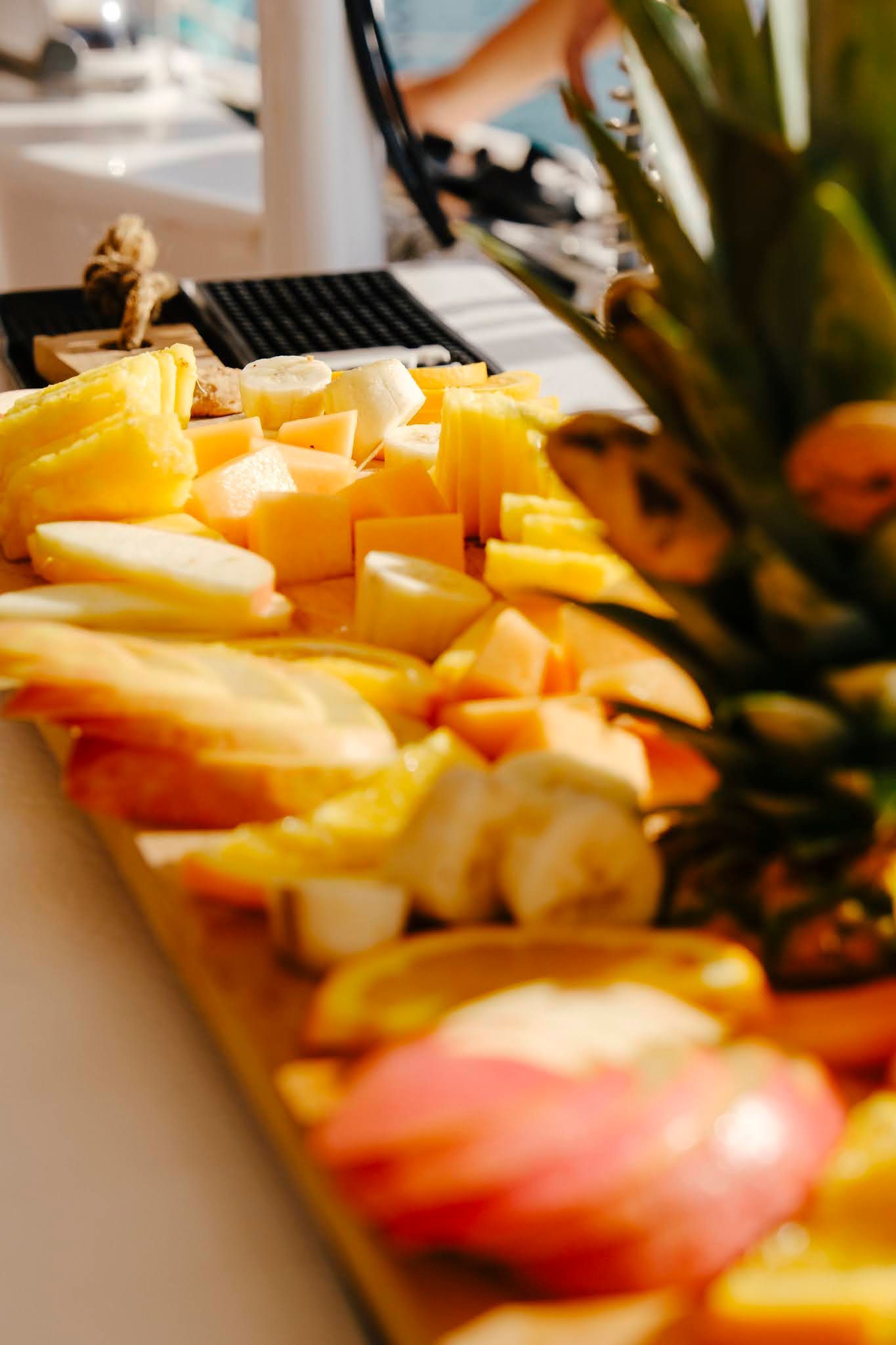Fruit platter with pineapple, apple slices, and other assorted fruits on a wooden board.