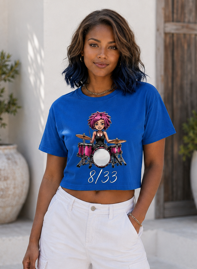 Woman standing outdoors wearing a blue graphic crop top and white pants.